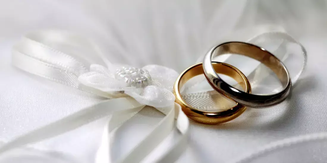 Two gold wedding rings on top of a white wedding cloth