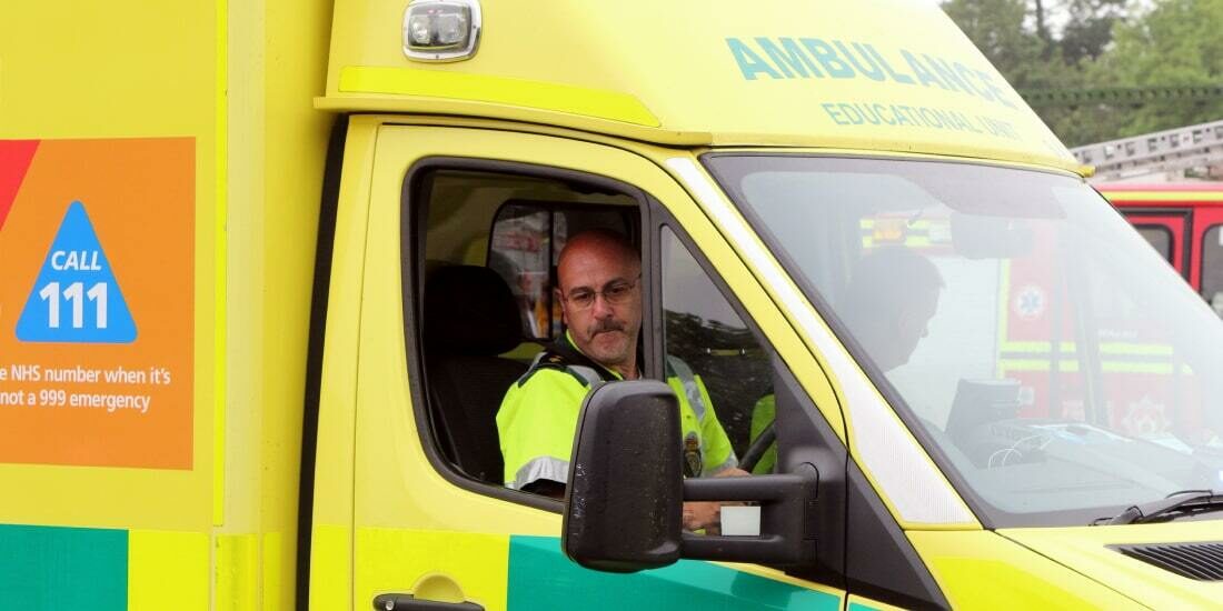 An ambulance driver checks his wing mirror as he reverses