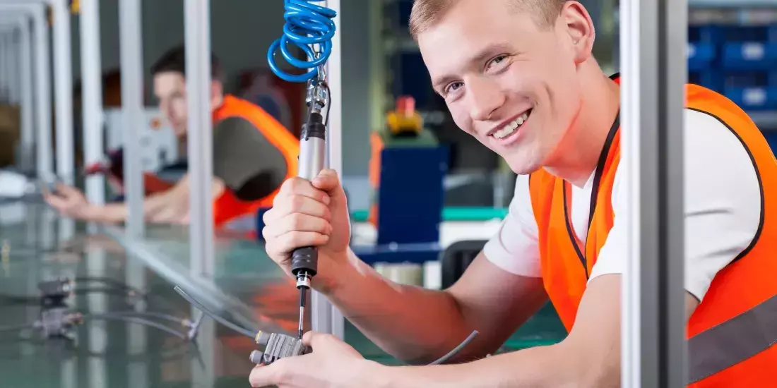 A production line employee smiles at the camera as he works