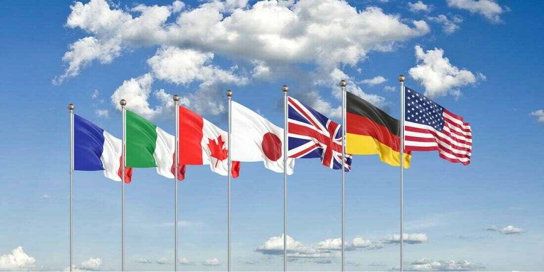 The flags of the G7 countries against a blue sky backdrop