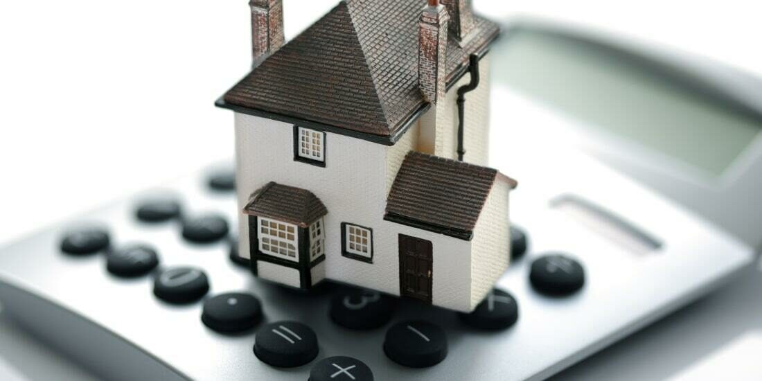 A model house sitting on top of a calculator