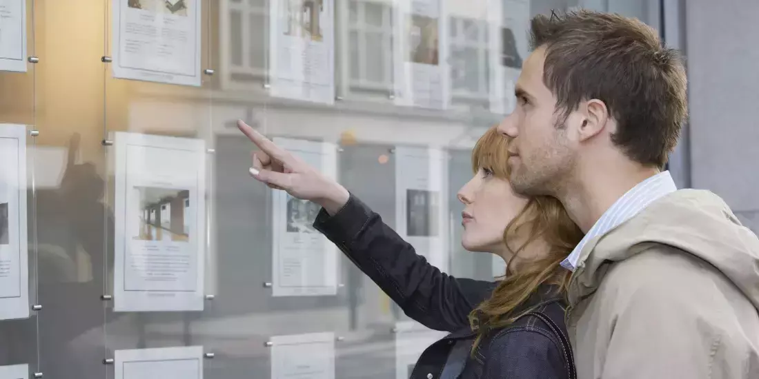 A couple looking at the window display of an estate agents